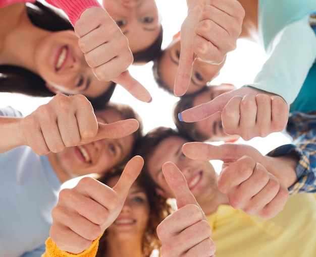 friendship, youth, gesture and people - group of smiling teenagers in a circle showing thumbs up