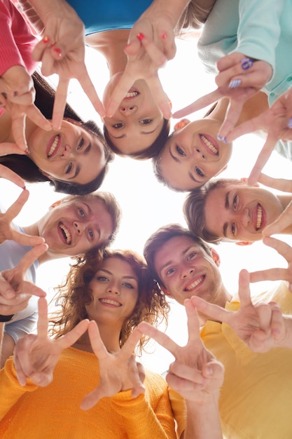 дружба, молодость, жест и люди - группа улыбающихся подростков в кругу, показывающая знак победы