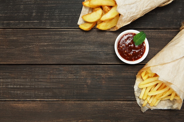 Fries and wedges potatoes on a wooden table