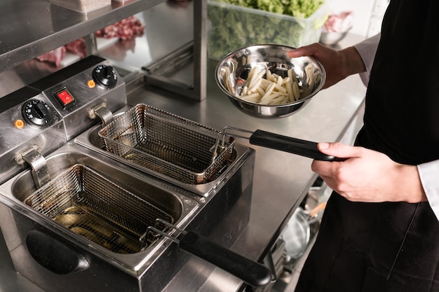 Frieten - beste junkfood ooit. Kok bereiden van fast food in de keuken van het restaurant.