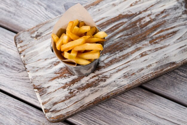 Frieten in een emmer. Bovenaanzicht van gele frietjes. Gerecht rijk aan vetten. Voorbeeld van bewerkt voedsel.