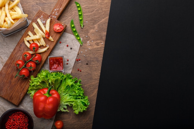 Frieten in een raster met ketchup, salade en cherrytomaatjes op houten tafel