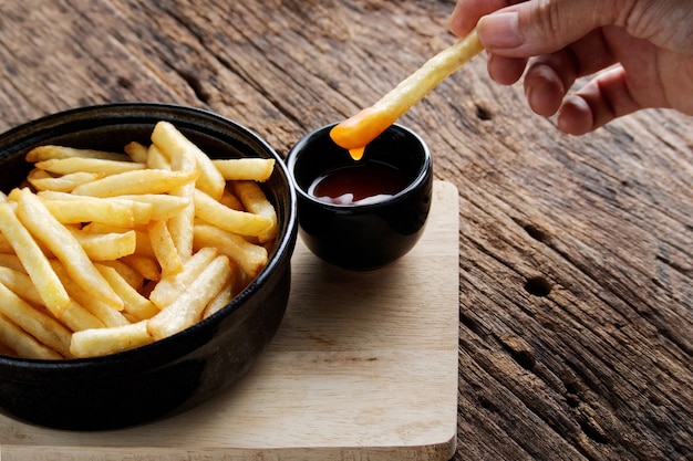 Frieten met ketchup op een donkere houten achtergrond. fastfood-snack.