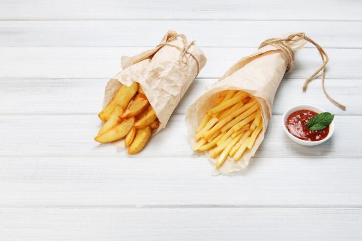 Frietjes en wiggen aardappelen op een houten tafel