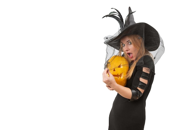 Photo frightened beautiful woman in a witch's hat and a jacko'lantern in her hands white background space for text halloween party