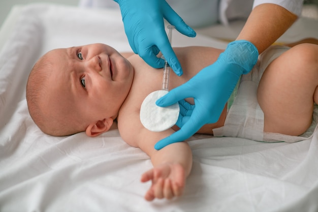 Frightened infant being injected a vaccine by a doctor