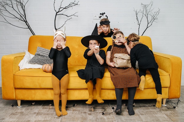 Frightened kids dressed for halloween sitting on couch watching scary movie