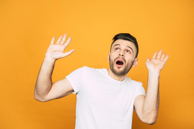 Frightened man next to the orange background is trying to protect himself from something dangerous above him