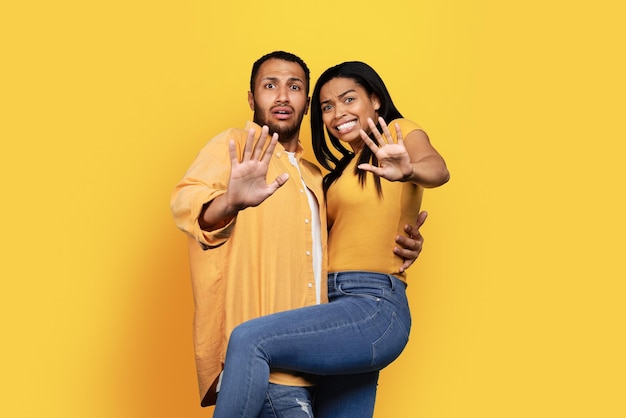 Frightened millennial african american male and wife making stop hand gesture afraid