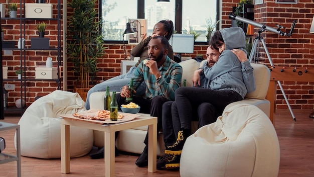 Frightened people watching scary horror movie on television, getting scared and screaming. Covering eyes after doing jump scare at thriller film, being shocked and afraid in front of tv.