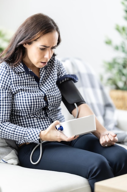 frightened woman after measuring blood pressure with a measuring device because of a bad result