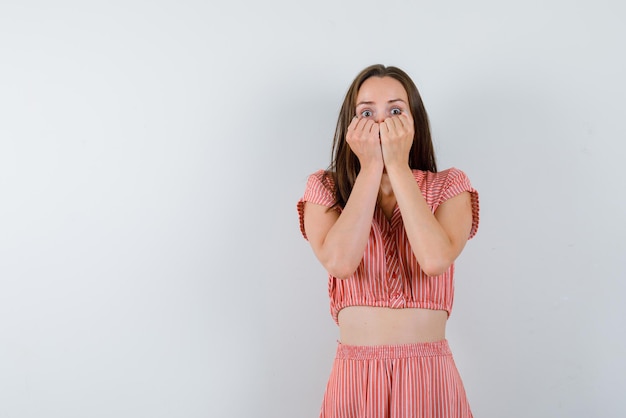 白い背景の上の彼女の口に彼女の拳を保持しているおびえた少女