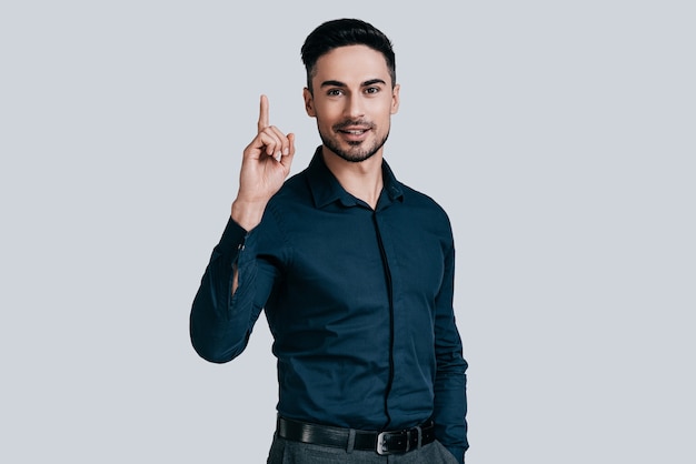 Fris idee. Knappe jonge man in shirt die vinger omhoog houdt en naar de camera kijkt