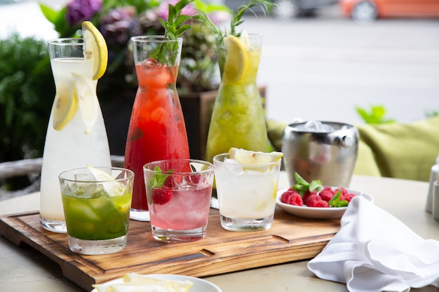 Frisdranken in de zomer, limonades. Limonades in kannen op de tafel, de ingrediënten waarvan ze zijn gemaakt, zijn rond gerangschikt.