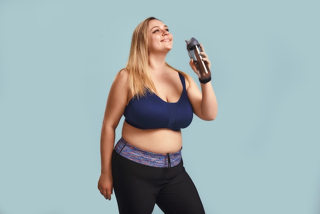 Frisse en gezonde jonge en gelukkige plus size vrouw in sportkleding met een fles