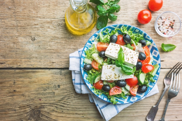 Frisse Griekse salade van komkommer, tomaat, paprika, rode ui, fetakaas en olijven met olijfolie. Gezond eten, bovenaanzicht