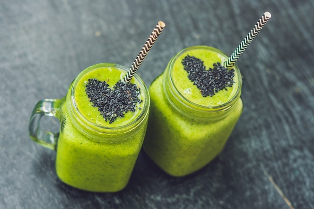 Frisse groene smoothie met banaan en spinazie met hart van sesamzaadjes. Liefde voor een gezond raw food concept