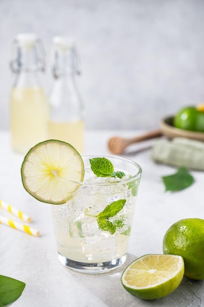 Frisse koude cocktail mojito met limemint en ijs Zomerconcept citrusdrank met limoenen op grijze achtergrond Vooraanzicht