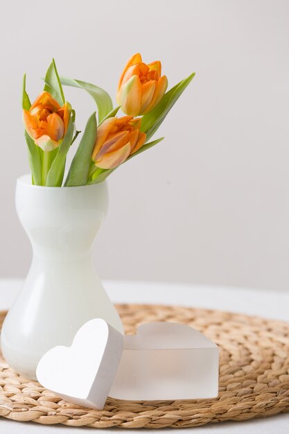 Frisse lente bos oranje tulpen in een mooie witte glazen vaas en twee schattige hartjes symbolen