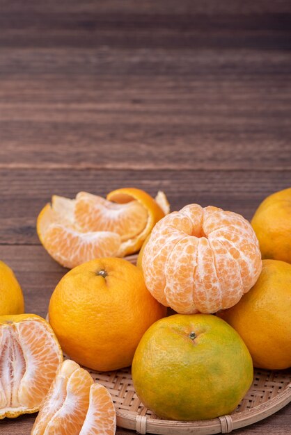 Frisse, mooie oranje kleur tangerine op bamboe zeef over donkere houten tafel. Seizoensgebonden, traditionele fruit van Chinees nieuw maanjaar, close-up.