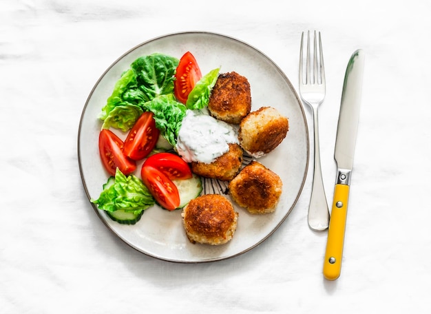 Frisse salade en ingeblikte tonijn-aardappelballetjes met Griekse yoghurt-cilantrosaus op een licht bovenaanzicht als achtergrond