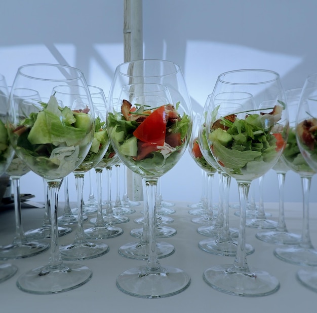 Frisse salade en spek in verrine-glas geserveerd op wit tafelkleed bij de voedselreceptie