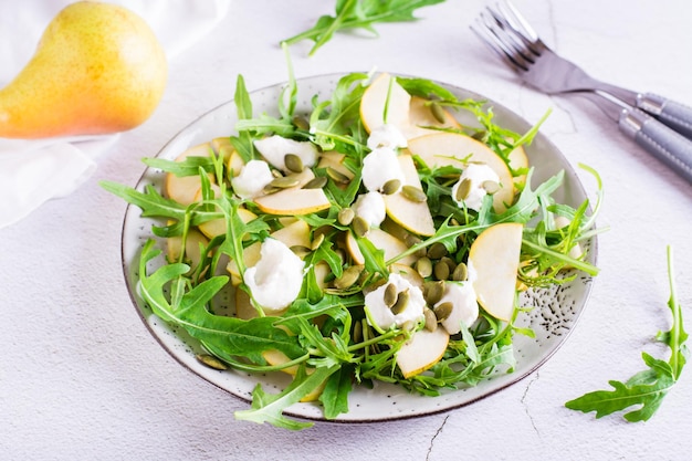 Frisse salade met peren rucola ricotta en pompoenpitten op een bord op tafel Huisgemaakte lunch