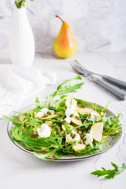 Frisse salade met peren rucola ricotta en pompoenpitten op een bord Zelfgemaakte lunch Verticale weergave