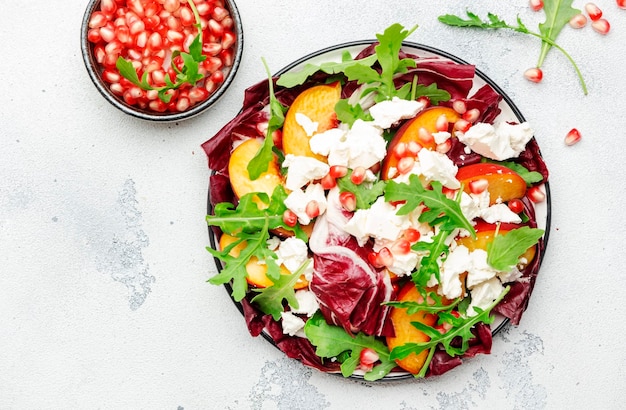 Frisse salade met rucola radicchio zoete perziken feta kaas en granaatappel zaden Witte tafel achtergrond bovenaanzicht