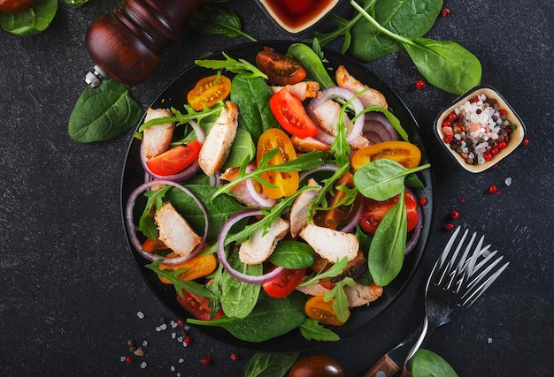 Frisse salade met spinazie kip tomaten rucola mais sla en ui Gezonde voeding Zwarte tafel