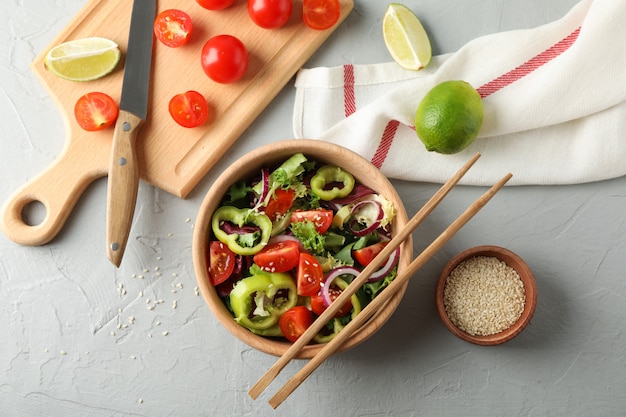 Frisse salade met stokjes en keuken accessoires op grijs