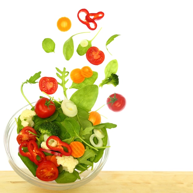 Frisse salade met stukjes die uit een geïsoleerde kom vliegen