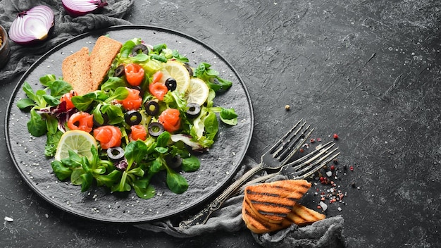 Frisse salade met zalm en olijven in zwarte plaat Bovenaanzicht Vrije ruimte voor uw tekst Rustieke stijl