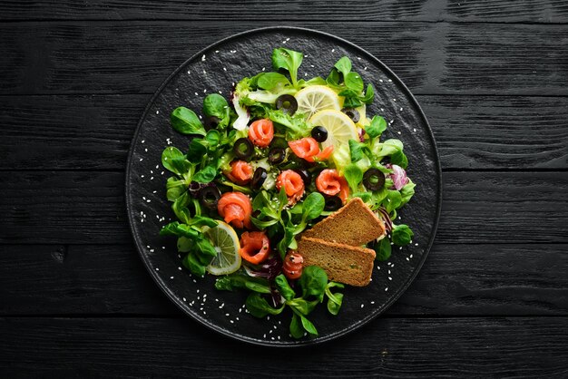 Frisse salade met zalm en olijven in zwarte plaat Bovenaanzicht Vrije ruimte voor uw tekst Rustieke stijl