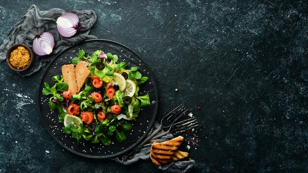 Frisse salade met zalm en olijven in zwarte plaat Bovenaanzicht Vrije ruimte voor uw tekst Rustieke stijl