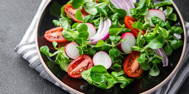 frisse salade plantaardig voedsel tomaat, radijs, mache sla, groene bladeren snackmaaltijd op tafel kopiëren