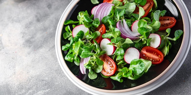 frisse salade plantaardig voedsel tomaat, radijs, mache sla, groene bladeren snackmaaltijd op tafel kopiëren