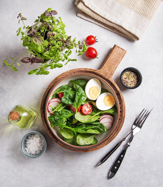 Frisse salade van groene spinazieblaadjes tomaten microgroenten basilicumgekookt ei rode radijs en olijfolie