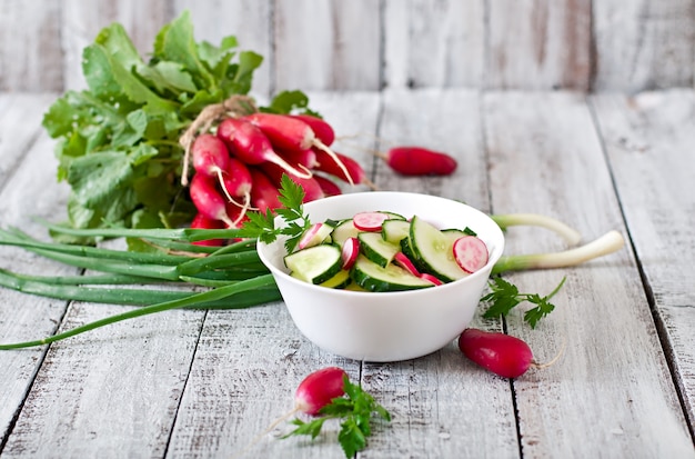 Frisse salade van komkommers en radijs in een witte kom