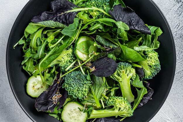 Frisse salademix van spinazie, rucola, snijbiet en veldsla met groenten. Witte achtergrond. Bovenaanzicht.