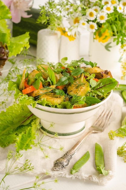 Frisse zomersalade met courgette wortelen en kruiden in een kom op een lichte houten tafel