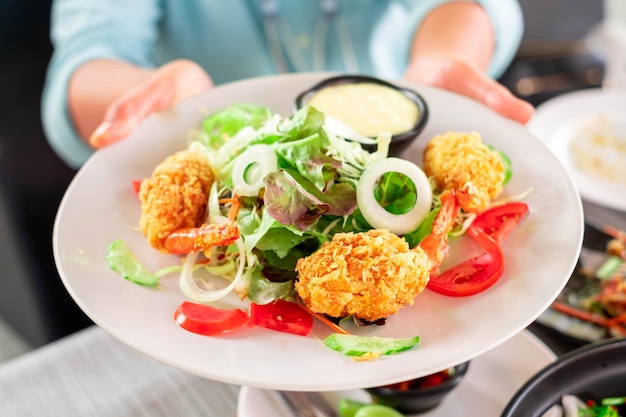 Frisse zomersalade met garnalen, cherrytomaatjes en komkommers in een kom op de vuurtafel Het concept van gezond eten