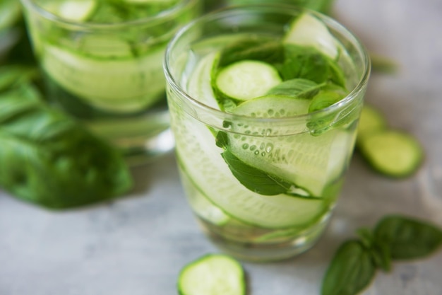 Frisse zomerse groene groentecocktail Mocktail met basilicumbladeren en komkommer Groene verse drank op een grijze achtergrond