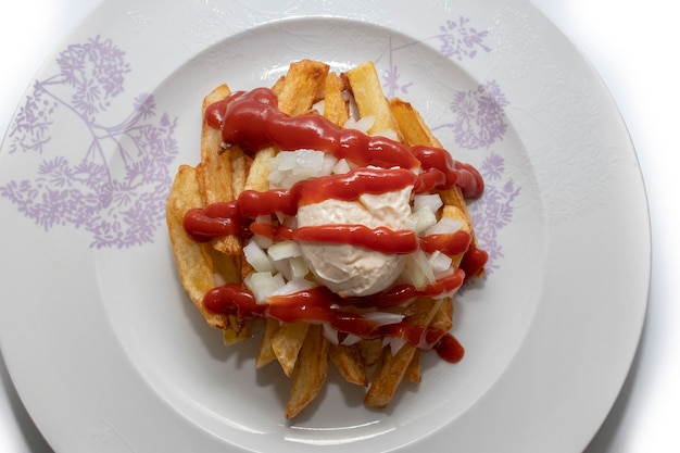 Foto frites spezial con maionese ketchup e cipolla su un piatto bianco isolato su sfondo bianco