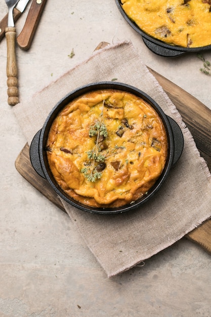 Frittata met champignons in een pan op houten achtergrond. Fritata is een Italiaans ontbijtgerecht.