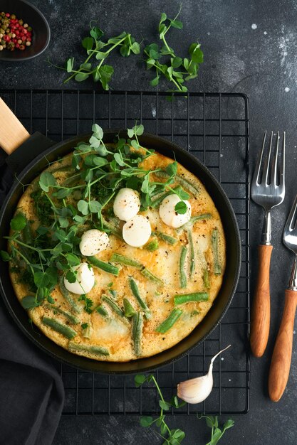 Frittata Omelet met spinazie en sperziebonen gezond eten in zwarte koekenpan op donkere oude rustieke achtergrond Gezond ontbijt heerlijk Bovenaanzicht plat lag Kopieer ruimte