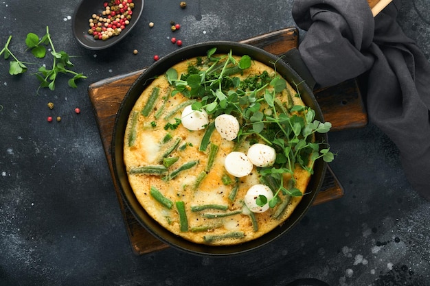 Frittata Omelet with spinach and green beans healthy food in black frying pan on dark old rustic background Healthy breakfast delicious Top view flat lay Copy space