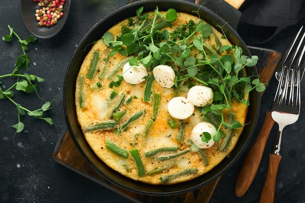 Frittata Omelet with spinach and green beans healthy food in black frying pan on dark old rustic background Healthy breakfast delicious Top view flat lay Copy space