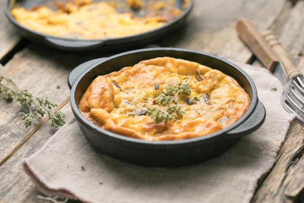 Frittata with mushrooms in a pan on wooden background. Fritata is an Italian breakfast dish.