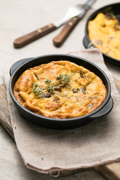 Frittata with mushrooms in a pan on wooden background. Fritata is an Italian breakfast dish.